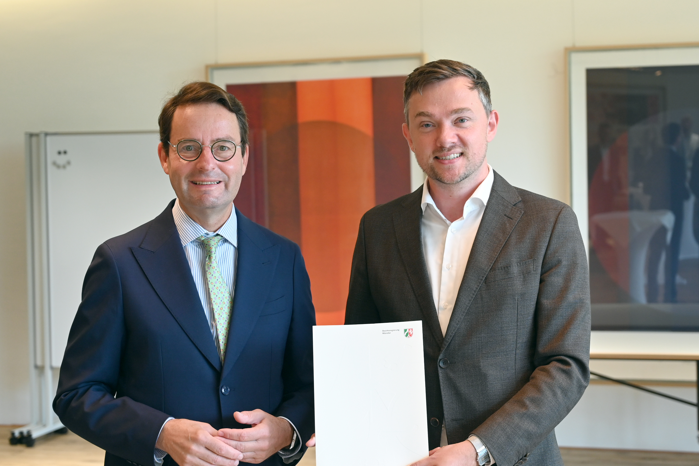 Regierungspräsident Andreas Bothe (l.) übergibt den Förderbescheid den Warendorfer Bürgermeister Peter Horstmann.