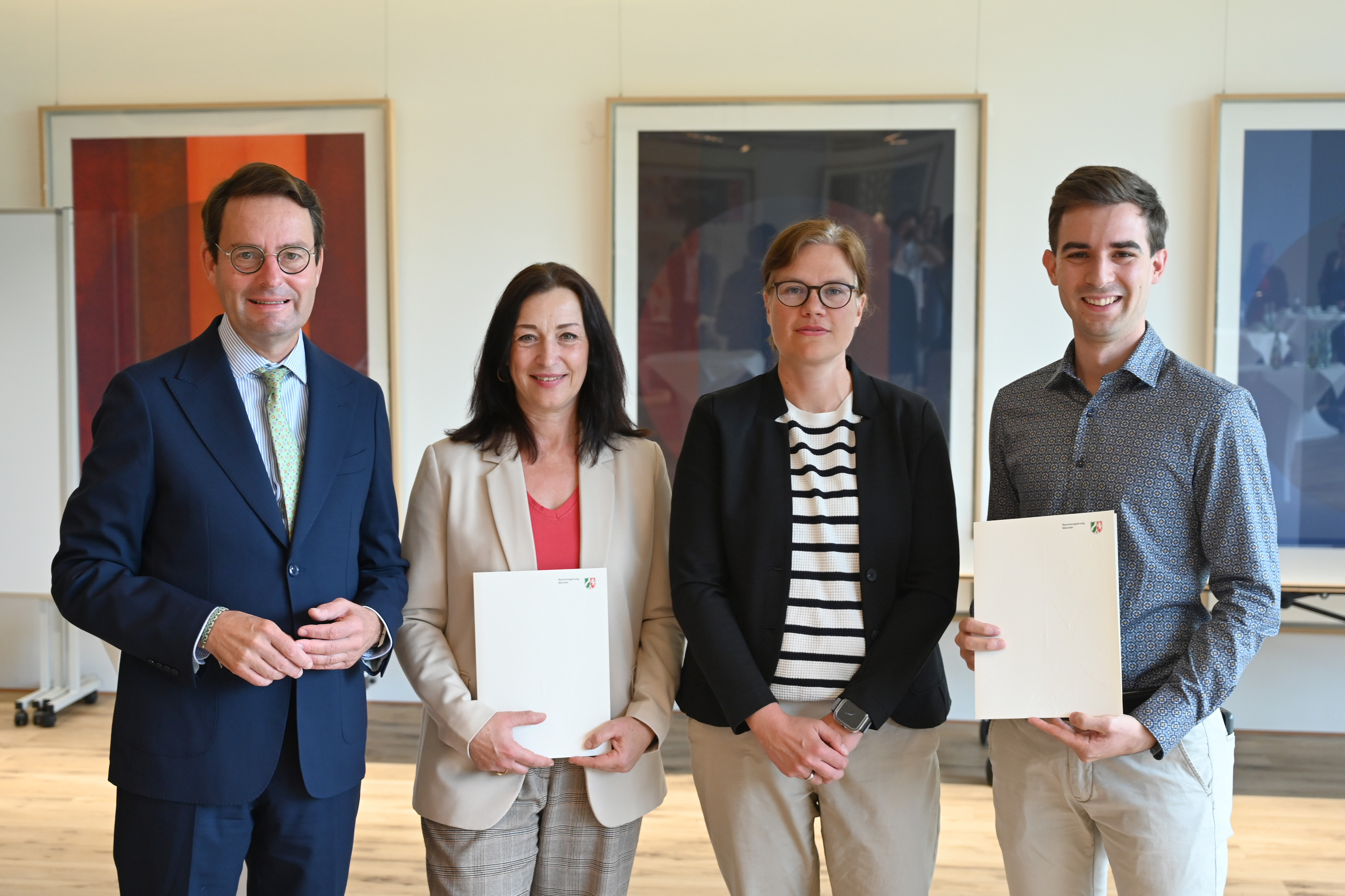 Regierungspräsident Andreas Bothe (l.) übergibt den Förderbescheid an Vertreter des Münsterland e.V. und der FH Münster. 